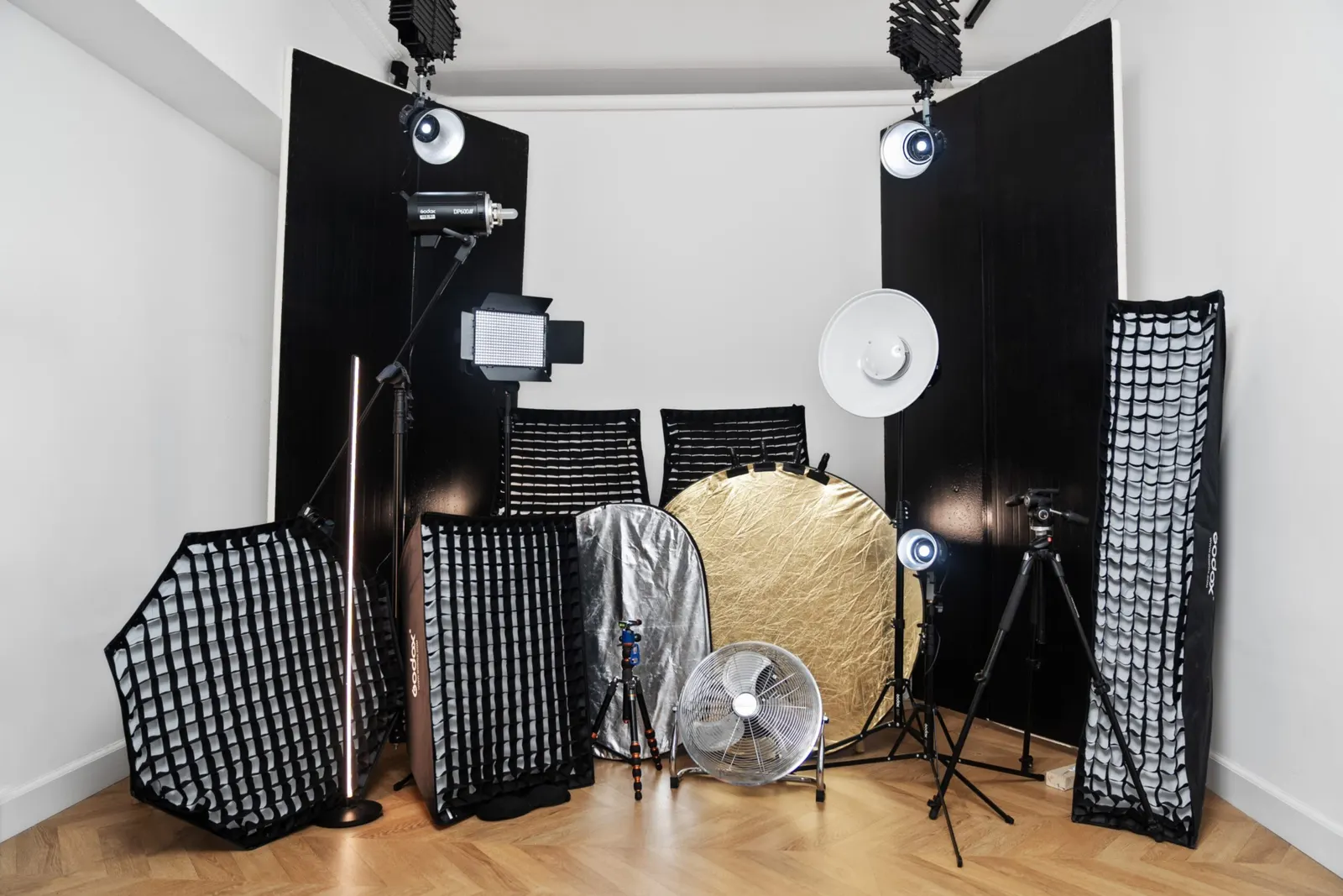 Matériel d'éclairage photo rangé dans un coin de studio : softbox, réflecteurs, trépieds